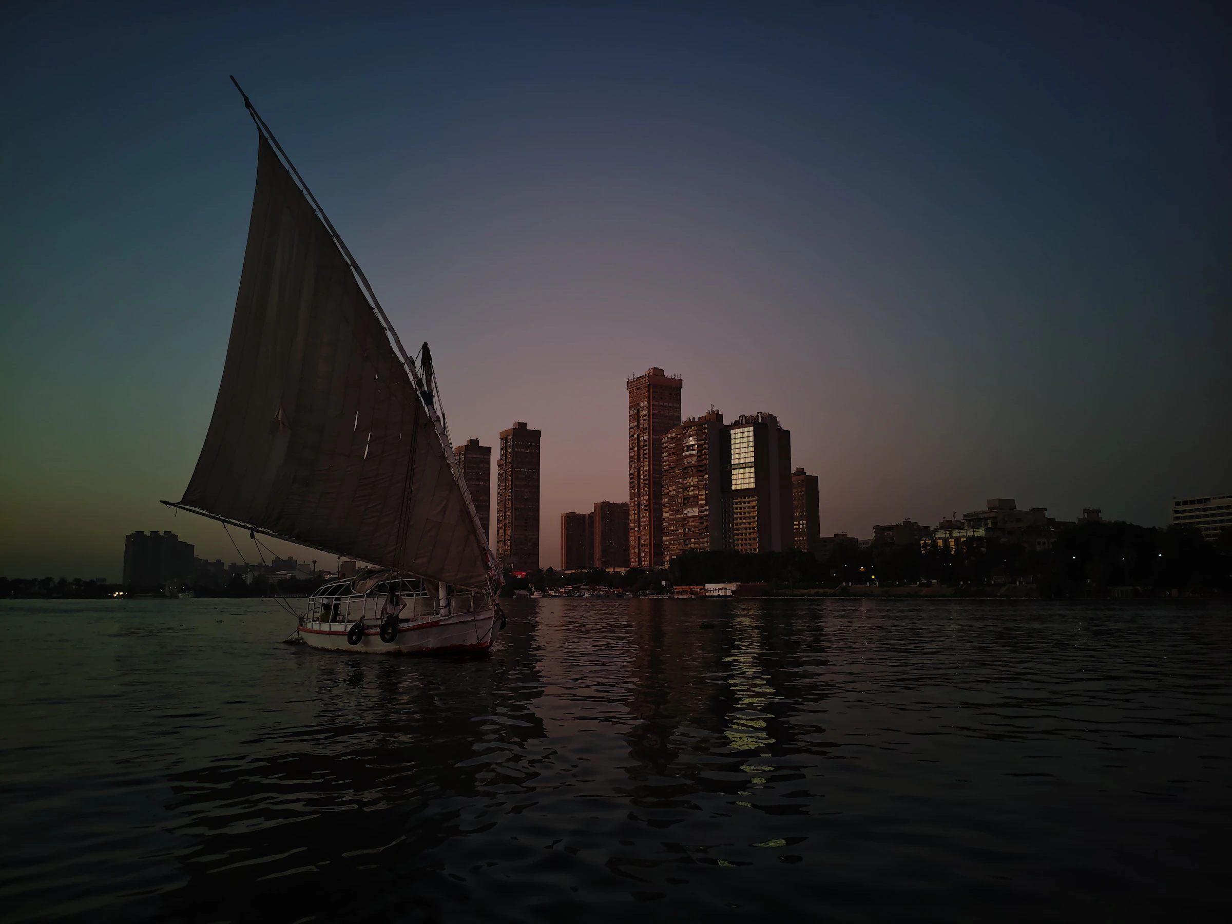 A felucca sails the Nile past Cairo towers at blue hour